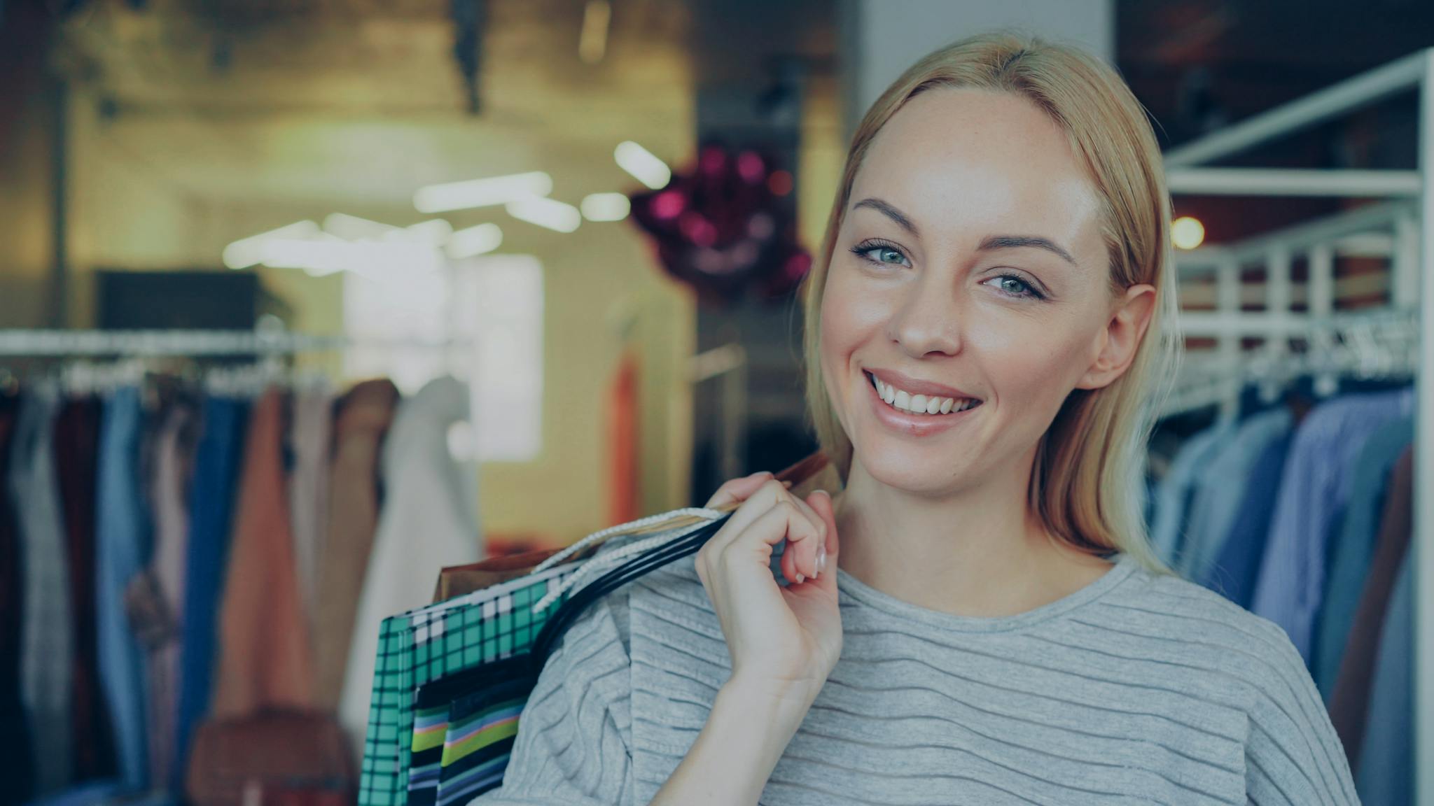 Delighted woman shopping in a stylish boutique, holding colorful bags.